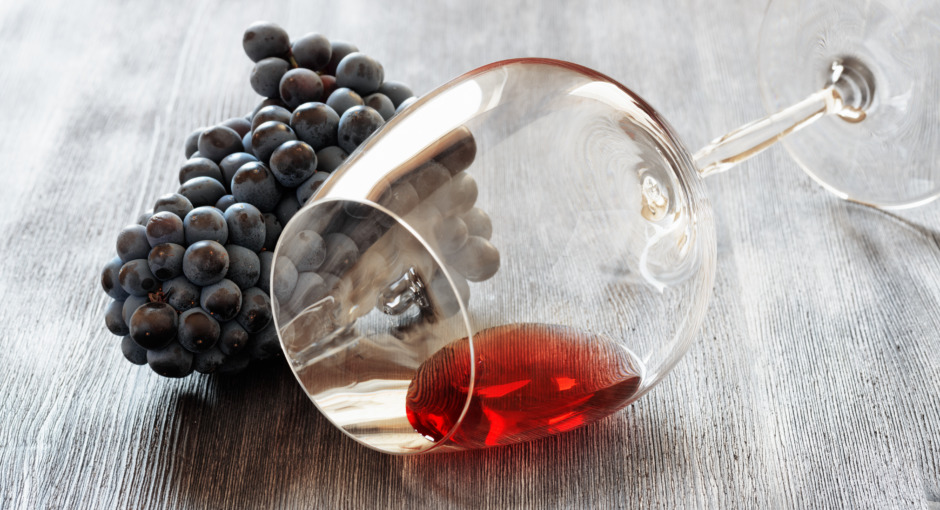 Wine glass with grape on wooden table.